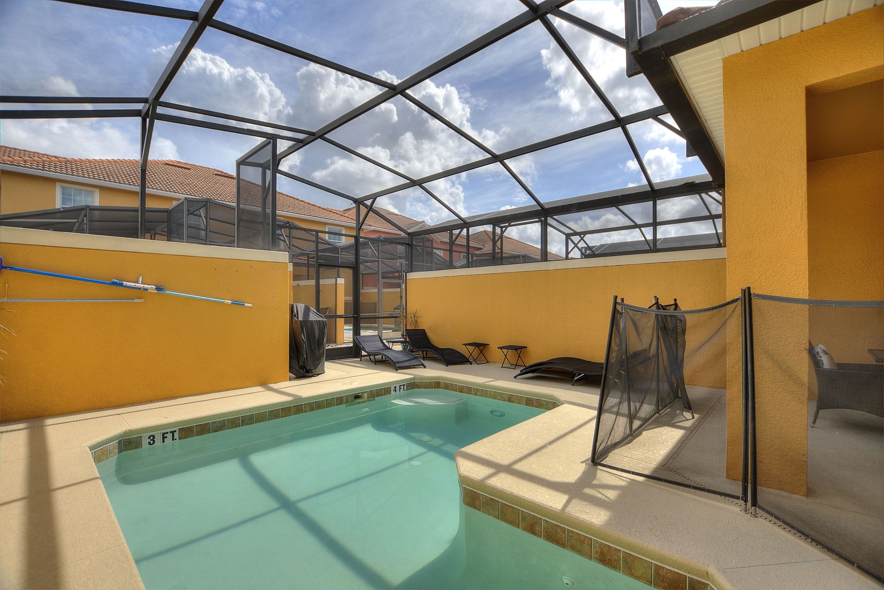 An indoor swimming pool with a glass ceiling, surrounded by lounge chairs and a covered seating area.