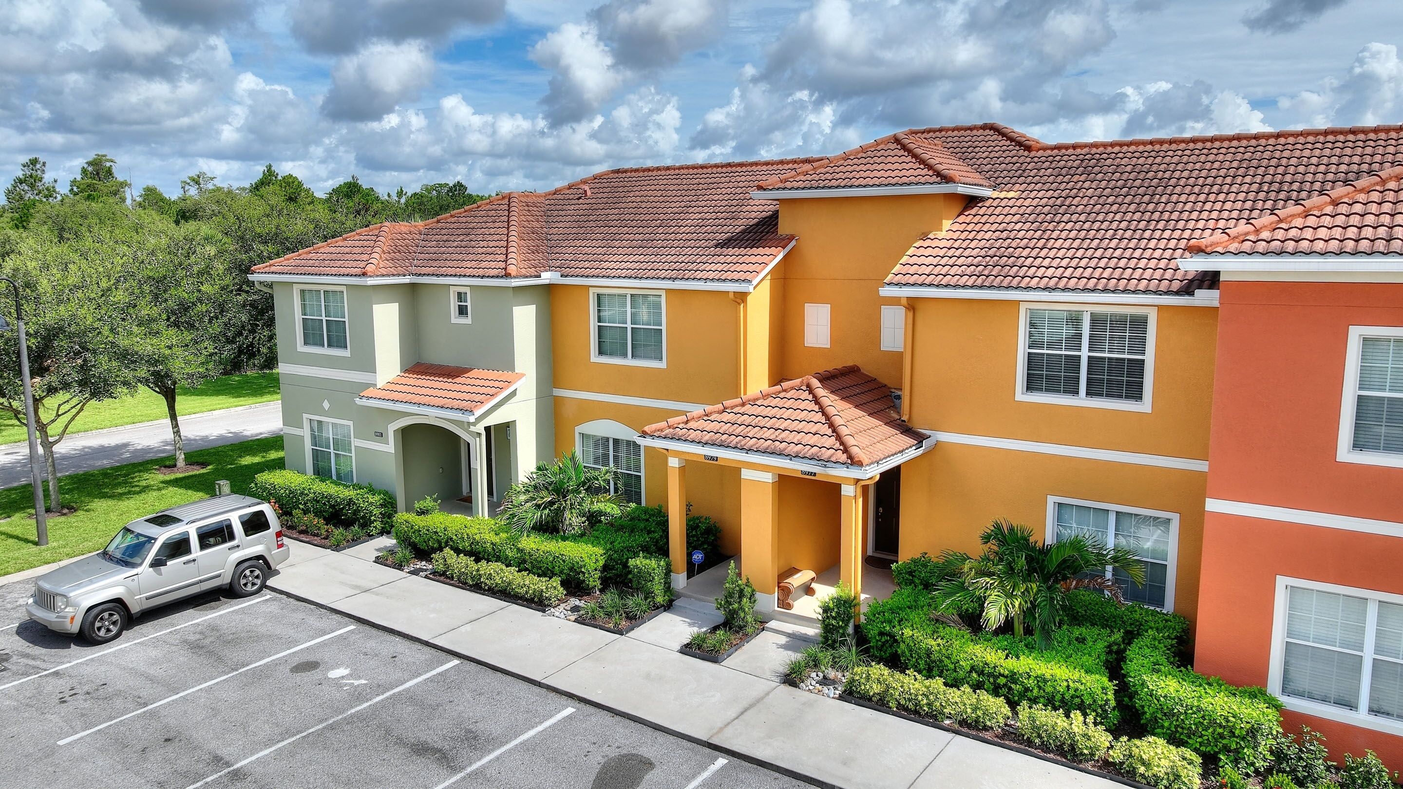 A multi-story residential building with a parking lot and green landscaping.