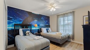 A hotel room with two beds, a ceiling fan, a large wall mural, a window with curtains, and a dresser. - Sunny Paradise Retreat At Paradise Palms By Shine Villas 4 Bedroom Townhouse (Kissimmee)
