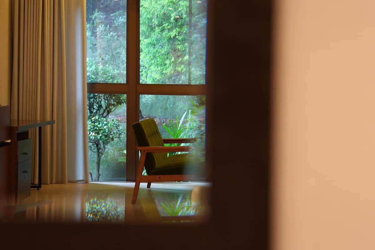 A room with a large window, a wooden chair, and a wooden table.