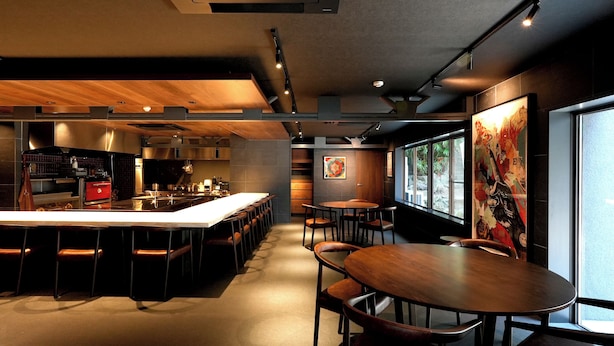 En modern restaurang med en lång bardisk, flera olika typer av sittplatser och ett stort fönster med utsikt.