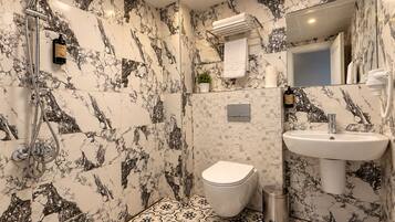Un baño con ducha, inodoro, lavamanos y paredes con diseño de mármol.