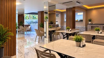 A modern dining area with marble flooring, wooden paneling, and multiple tables and chairs.