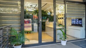 A hotel entrance with a reception desk, a TV screen, and potted plants. - Housr Sector 42 Gurgaon Golf Course Road (Gurugram)