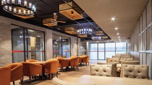 A modern conference room with wooden tables and chairs, large windows, and a high ceiling with exposed beams and lighting fixtures. - Housr Sector 42 Gurgaon Golf Course Road (Gurugram)