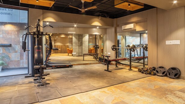 A gym with various exercise equipment, including a treadmill, weight bench, and free weights. - Housr Sector 42 Gurgaon Golf Course Road (Gurugram)