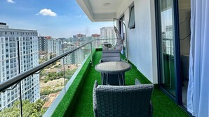 Un balcon avec un revêtement de sol en gazon synthétique, des meubles en osier et une porte vitrée.