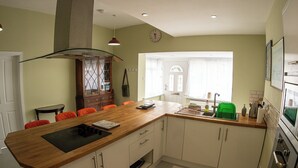 A kitchen with a wooden island, white cabinets, a built-in oven, and a window with curtains.