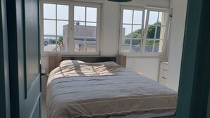 A bedroom with a bed, two windows, a nightstand, and a dresser.