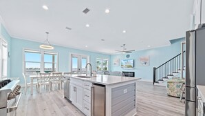 A modern kitchen with a central island, stainless steel appliances, and a view to the outside.