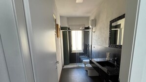 A narrow hallway leading to a bathroom with a shower, toilet, and sink. - The better (San Giorgio a Cremano)