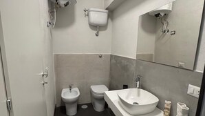A modern bathroom with a white sink, a bidet, and a toilet. - The better (San Giorgio a Cremano)