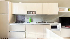 A modern kitchen with white cabinets, a gas stove, a microwave, and a sink.