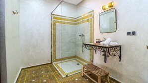 A bathroom with a shower, a sink with a towel rack, and a mirror. - Ferme d'hôte Zomorroda (Saâda)