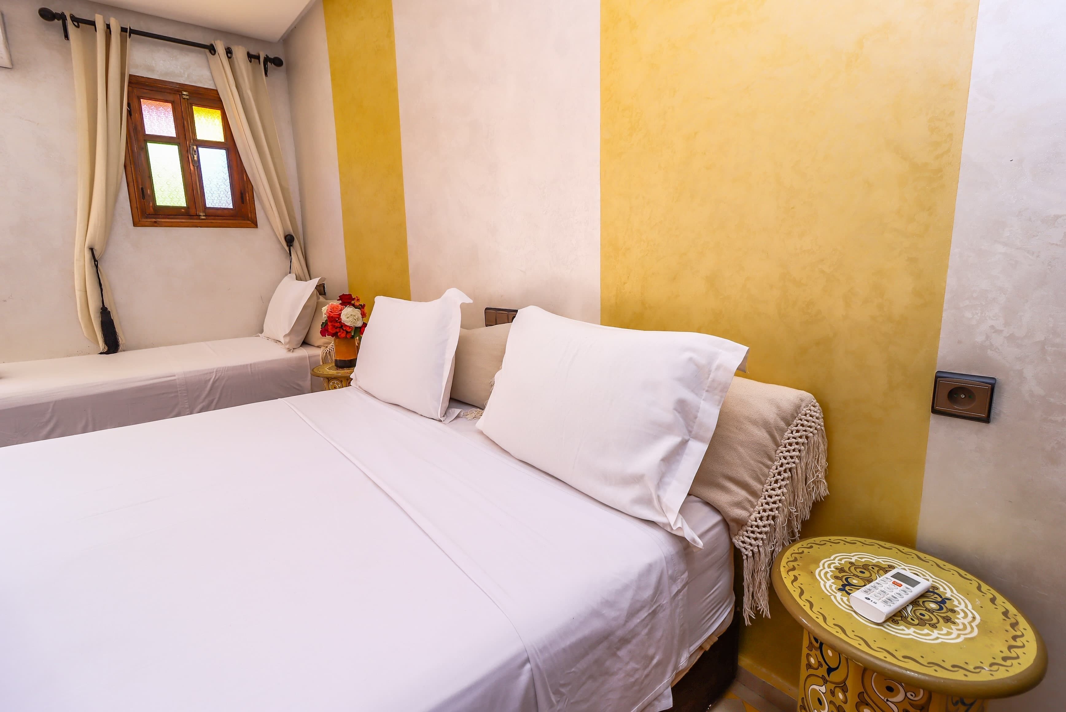 A bedroom with a bed, a bedside table with a book, and a window with curtains.