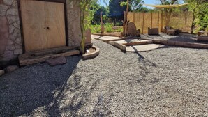 Un patio con un muro de piedra, una puerta de madera y mobiliario exterior.