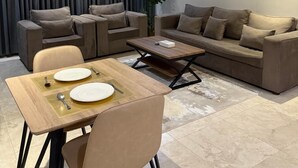 A modern living room with a dining area, featuring a sofa set, a coffee table, and a dining table with chairs.