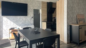 Ett modernt matområde med ett stort bord, stolar och en tv som är monterad på väggen.