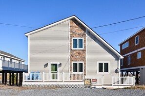 A two-story building with a stone accent wall, a front porch with railings, and a sign indicating it is for rent. - OceanFront 8 Bedroom! (South Bethany)