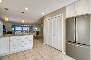 A modern kitchen with a central island, built-in cabinets, a stainless steel refrigerator, and a dining area with chairs. - OceanFront 8 Bedroom! (South Bethany)