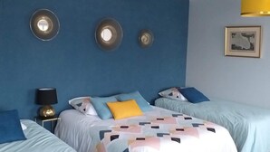 Habitación de hotel con dos camas, una pared azul y un cuadro enmarcado.