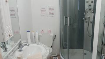 Een douche, handdoeken, zeep, toiletpapier