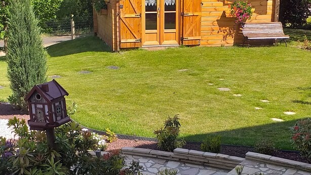 Una cabaña de madera con puerta principal, ventanas y un pequeño porche.