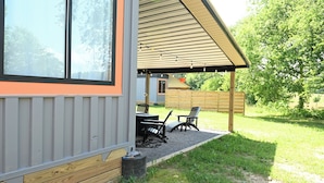 Un patio techado con mobiliario exterior y vistas del entorno.