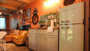 Una cocina con un refrigerador antiguo, armarios de madera y un respuesto de ladrillo.
