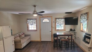 Una cocina compacta con comedor, ventilador de techo, refrigerador, horno empotrado y televisión.