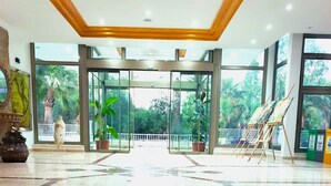 A spacious lobby with marble flooring, a staircase leading to upper floors, and large glass doors offering a view of greenery outside. - Softa Vivanco Hotel (Bozyazi)