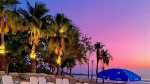 A beach with white lounge chairs and a blue umbrella. - Softa Vivanco Hotel (Bozyazi)