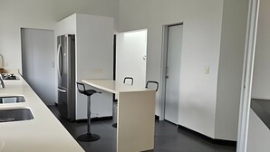 Et moderne køkken med et rustfrit stål køleskab, en hvid bordplade og en barstol.