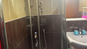 A bathroom with a glass-enclosed shower, a sink with blue soap dispensers, and a mirror above the sink. - Mik Apartments Heart of Budva 1+1 40sqm (Budva)