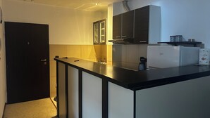 A compact kitchen with a black countertop, a white refrigerator, and a built-in oven. - Mik Apartments Heart of Budva 1+1 40sqm (Budva)