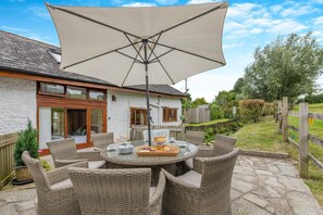 A patio with wicker furniture, a round table, and a large umbrella.