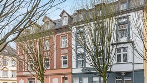 A row of multi-story residential buildings with a mix of architectural styles, parked cars, and leafless trees. - Central location... Ideal for business people, fitters...3 rooms, WiFi, SmartTVs (Mettmann)
