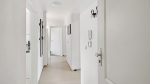 A bright, white hallway with a modern design, featuring a door with a telephone and a wall-mounted light fixture. - Central location... Ideal for business people, fitters...3 rooms, WiFi, SmartTVs (Mettmann)