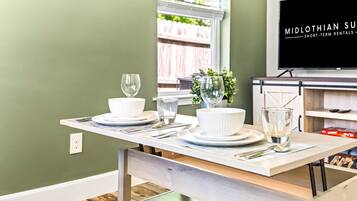 A dining table set with white dishes, glasses, and a vase with greenery.