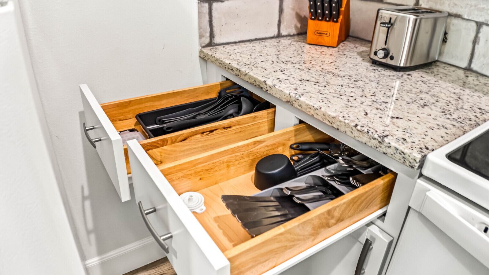 Une cuisine avec un tiroir contenant des ustensiles et un grille-pain posé sur le plan de travail.