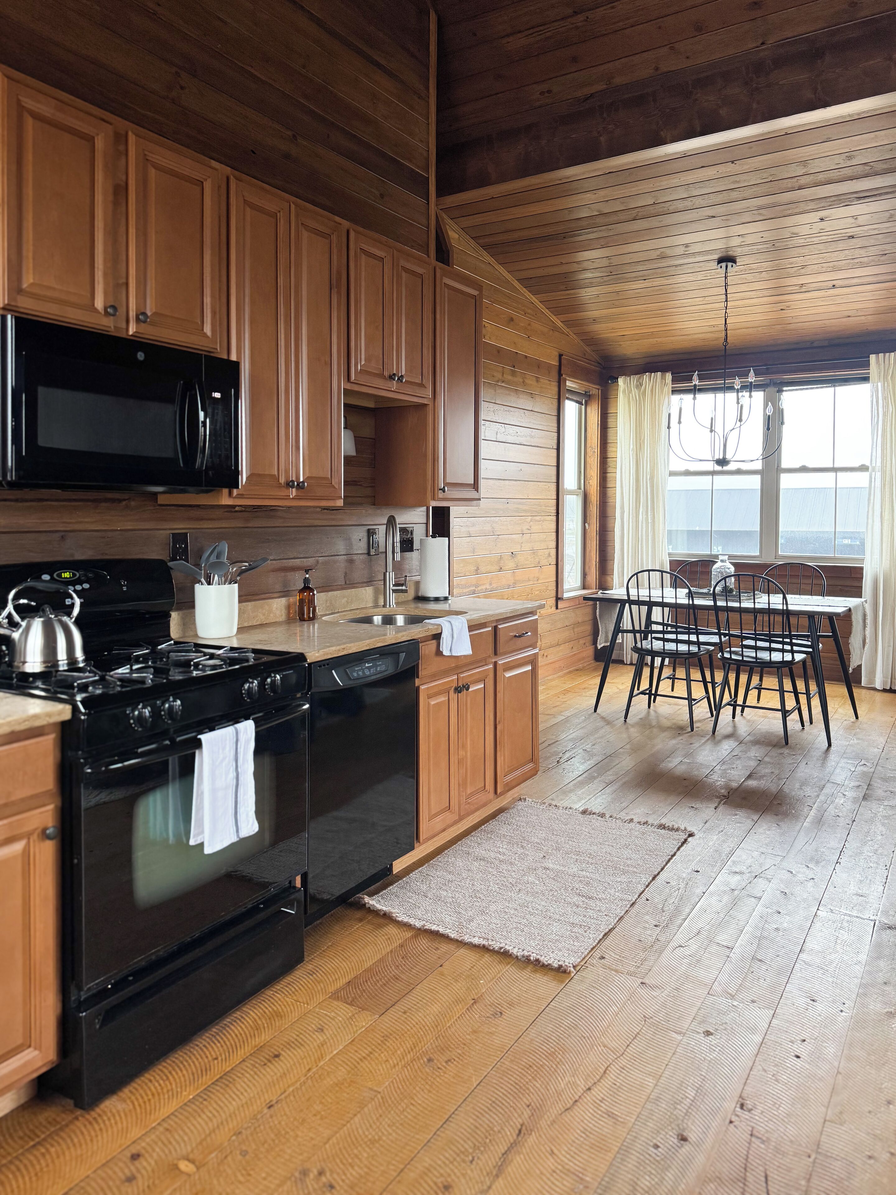 A kitchen with wooden cabinets, a stove, and a dining area with a table and chairs.