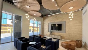A modern lounge area with seating, a TV, and large windows offering views of the outside.