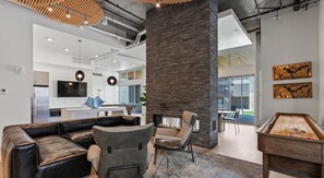Un espace de détente moderne avec des canapés en cuir, une table de billard et un pilier en pierre.