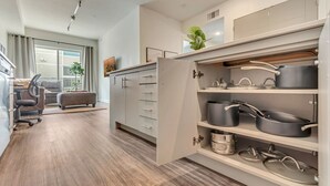 A modern kitchen with grey cabinets, a built-in oven, and a dining area with a grey sofa and a dining table. - Urban Retreat – Prime Location, Resort Amenities, Free Parking! (Salt Lake City)