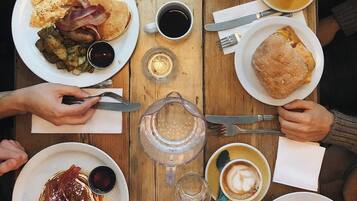 A wooden table with various breakfast items including pancakes, eggs, bacon, and toast.