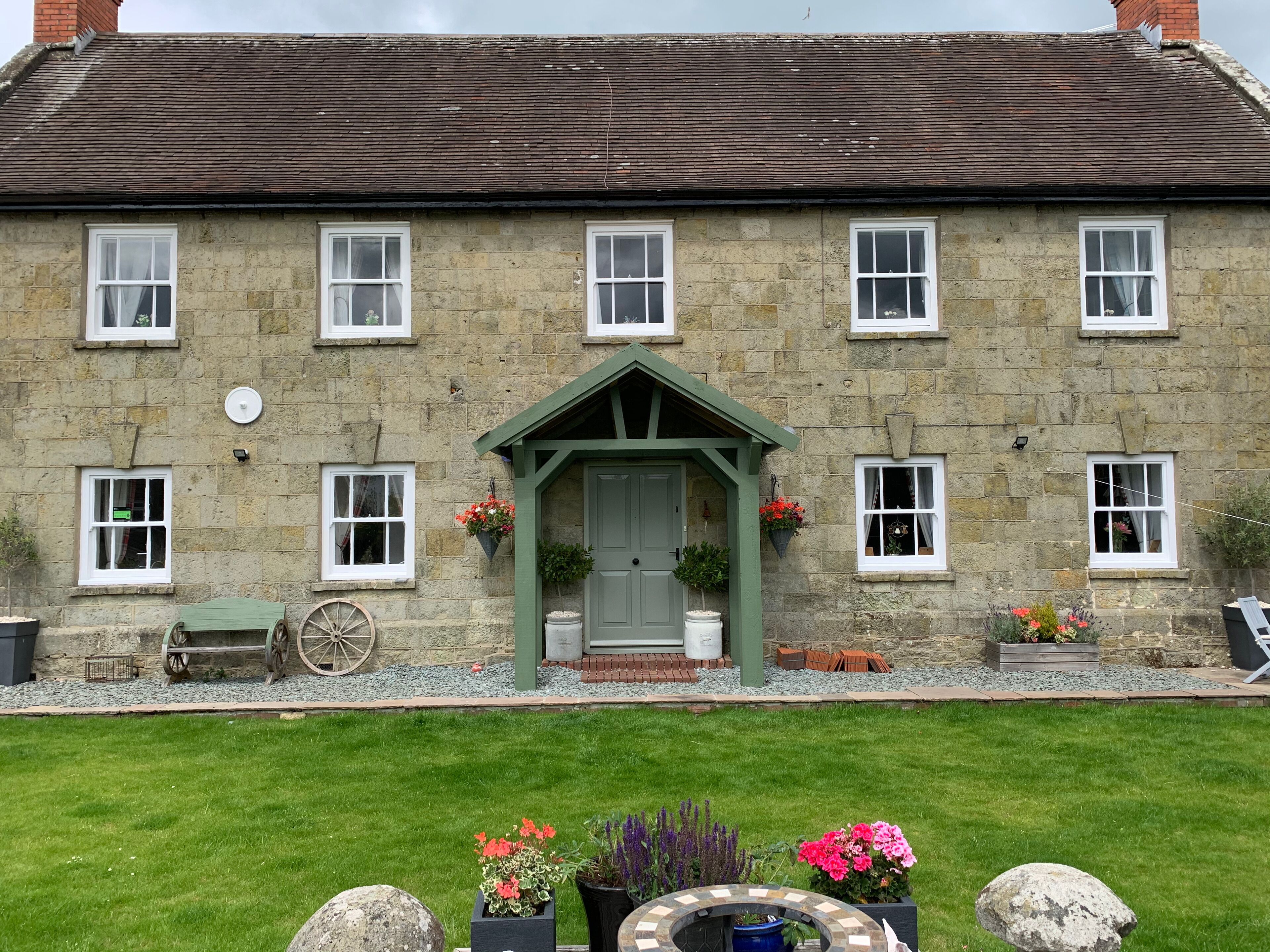 A stone building with a green door and multiple windows.