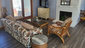 Una sala de estar con sofá, sillón, mesa de centro, televisor, chimenea y aparador.
