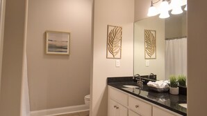 A bathroom with a black countertop, white cabinets, a mirror, and a ceiling light. - Cozy 2-bedroom condo in charming Townsend with WiFi, AC (Townsend)