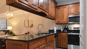 A kitchen with wooden cabinets, a stainless steel refrigerator, a microwave, and a dishwasher. - Cozy 2-bedroom condo in charming Townsend with WiFi, AC (Townsend)
