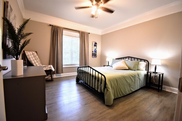 A bedroom with a bed, bedside tables, a ceiling fan, a window with curtains, and a potted plant. - Cozy 2-bedroom condo in charming Townsend with WiFi, AC (Townsend)